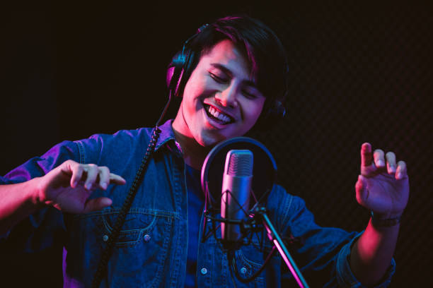 istock Asian male singer recording songs by using a studio microphone and pop shield on mic with passion in a music recording studio. Performance and show in the music business. Image with copy space. 1332147594
