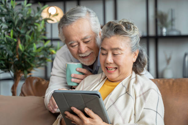 istock old asian senior couple sit relax happiness on sofa hand use tablet device with laugh smile together home isolation ideas concept 1332148826
