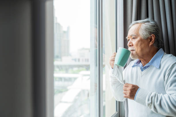 istock old asian senior retired age standing hand hold hot drink look outside window home isolate concept,old man waiting for lockdown is over home interior background 1332148833