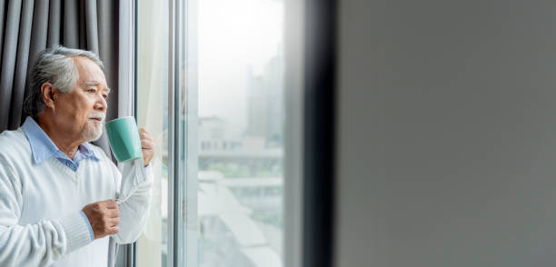 istock old asian senior retired age standing hand hold hot drink look outside window home isolate concept,old man waiting for lockdown is over home interior background 1332148837