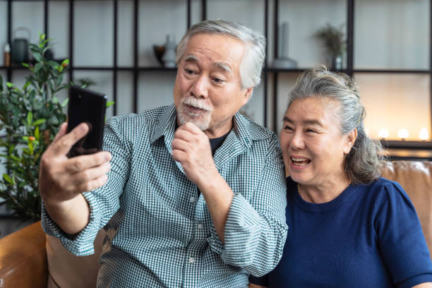 happiness asian old senior retired couple enjoy videocall to family together on sofa in living room at home,asian people use smartphone communication to family home isolation ides concept felicidad asiática vieja pareja jubilada disfrutan de videollamada a la familia juntos en el sofá en la sala de estar en casa, las personas asiáticas utilizan la comunicación de teléfonos inteligentes para el concepto de idus de aislamiento en el hoga