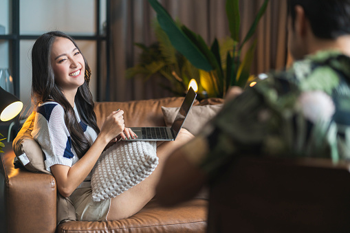 home isolation together asian female laugh smilie conversation with her caucasian husband at living room,family relation home quarantine ideas concept