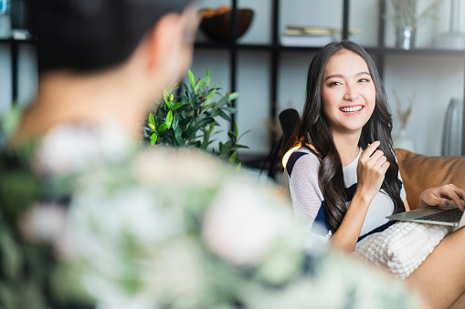 home isolation together asian female laugh smilie conversation with her caucasian husband at living room,family relation home quarantine ideas concept