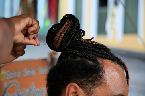 salvador, bahia, brazil - july 27, 2021: hairdresser is seen braiding tourist hair in Pelourinho, Historic Center of Salvador city.