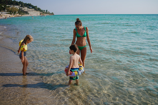 Mother putting on swim arm bends and inflatable ring for swimming