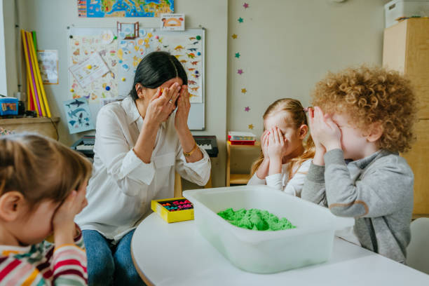 istock Preschool students playing with teacher in hide and seek 1332150744