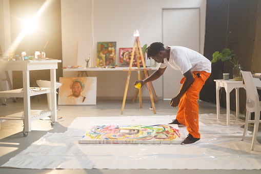 African american male painter at work painting on canvas in art studio. creation and inspiration at an artists painting studio.