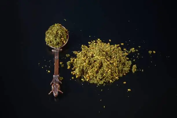 Photo of Zaatar or Zather is name of middle eastern spice herbal mix with sumac,thyme,oregano,bible hyssop and sesame seeds on black background in vintage oriental design spoon.