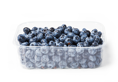 Fresh organic blueberries in a transparent plastic tray. Dark blue ripe fruits of Vaccinium corymbosum. Close-up, isolated on white background with clipping path