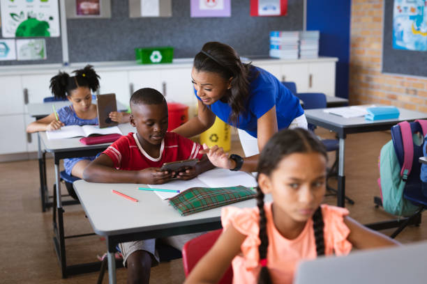 istock African american female teacher teaching a boy to use digital tablet in class at elementary school 1332153994