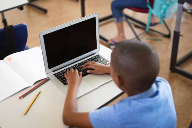 istock African american boy using laptop while sitting on his desk in the class at elementary school 1332156264