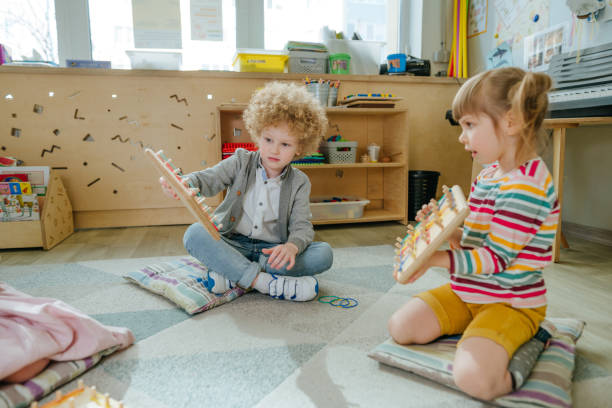 istock Preschool students playing with geoboard wrapping rubber bands in kindergarten 1332156644