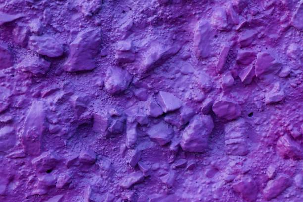 istock Decorative relief plaster. Violet painted relief wall with rough chaotic convex elements. Abstract texture of concrete wall covered uneven decorative stucco and painted bluish-purple paint 1332156695