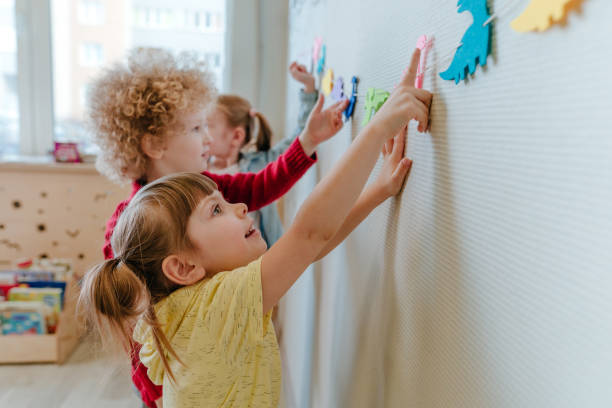 Preschool students playing in kindergarten with color dinosaur figures