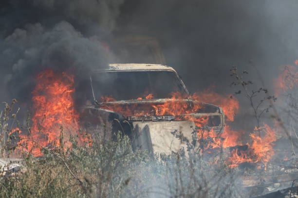 istock Burning car in a field covered by fire 1332156822