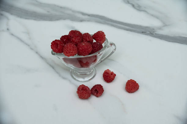 istock A glass cup with ripe raspberries on the kitchen table. 1332158472