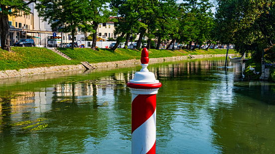 view of canal with red and white pole in Dolo, Venice, Italy