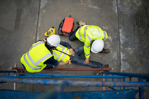 Builder injury accident falling scaffolding to the floor. Basic first aid training for support accident in site work, Safety team help employee accident.