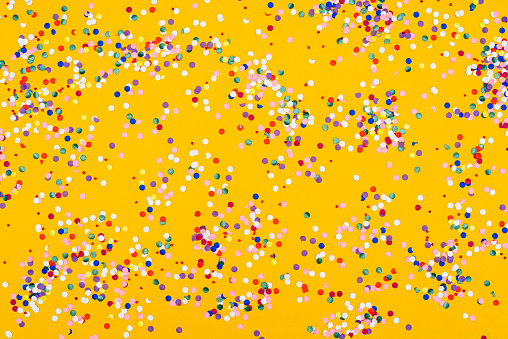 High angle view of confetti colored papers background on yellow paper