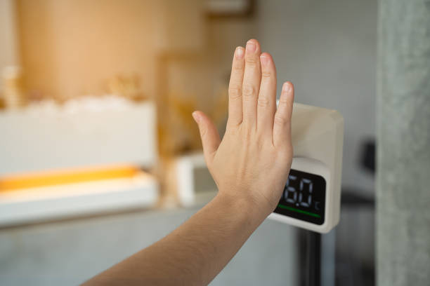 istock Women hand checking temperature before entering cafe with digital automatic body measuring temperature check machine 1332166870