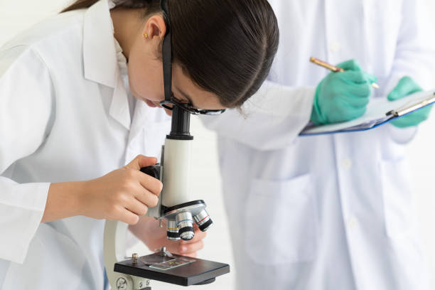 istock Child girl scientists looking germs and bacteria through microscope in laboratory. Scientific experiment. Early development of children 1332167003