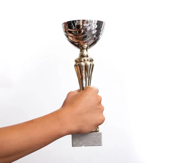 arms holding up cup with white background , concept of winning and success .