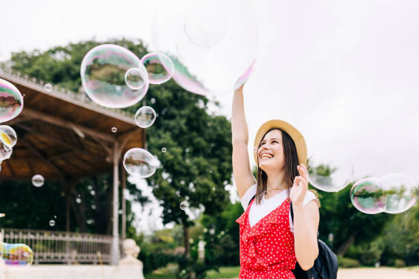 istock Joyful young hispanic woman having fun while playing with soap bubbles in city park - Smiling cheerful hipster female tourist enjoying her summer holidays - Travel lifestyle concept 1332168448