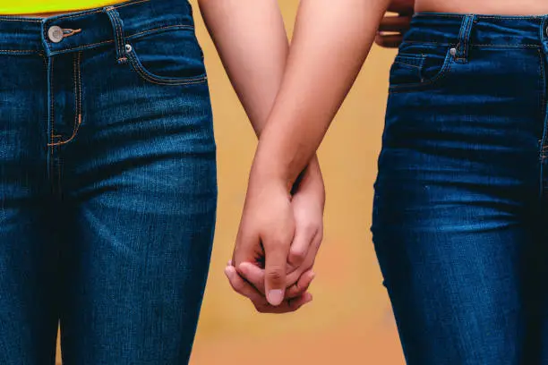Photo of close up of two unrecognized women hands together, diversity, lesbian love concept.