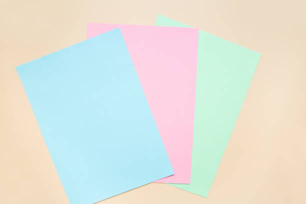 istock Blank sheets of blue, pink and green colored paper on a beige background. Layout, copy space. 1332170775