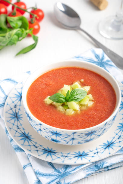 cold gazpacho spanish refreashing summer soup made of pureed vegetables mostly tomatoes decorated with cucumber and basil leaf served in bowl with spoon on white wooden table - basil tomato soup food and drink imagens e fotografias de stock