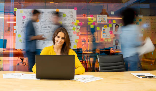 istock Woman working at a creative office using her computer and people moving at the background 1332176258