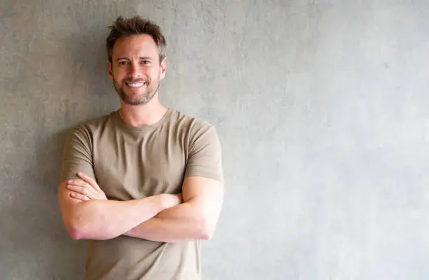 Happy Latin American man looking at the camera smiling with arms crossed - studio shot