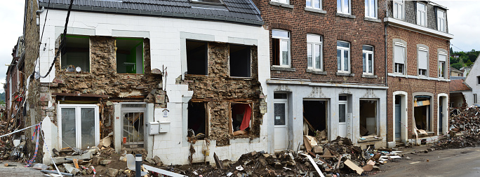 Pepinster, Liège, Belgium- August,01, 2021: 2 weeks after flood still damage visible in the streets. Houses without glass in window frames. Garbage from flood cleaned in a heap aside the road on footpath. Corner house facade collapsed. Like a war scene.