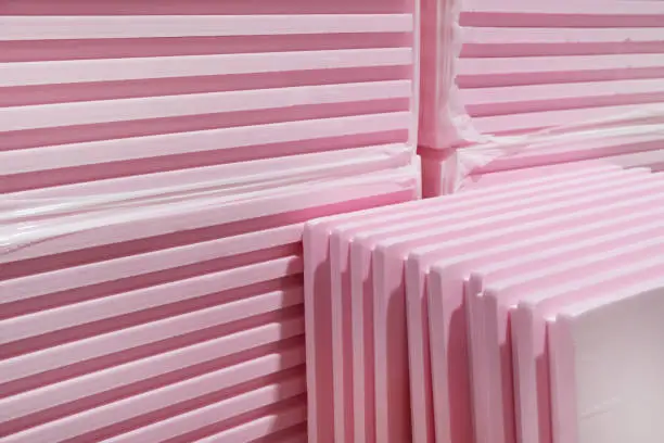 Photo of Pink Extruded Polystyrene XPS foam thermal insulation boards  stacked in construction site. High Density, water absorption. Eco energy saving  technology