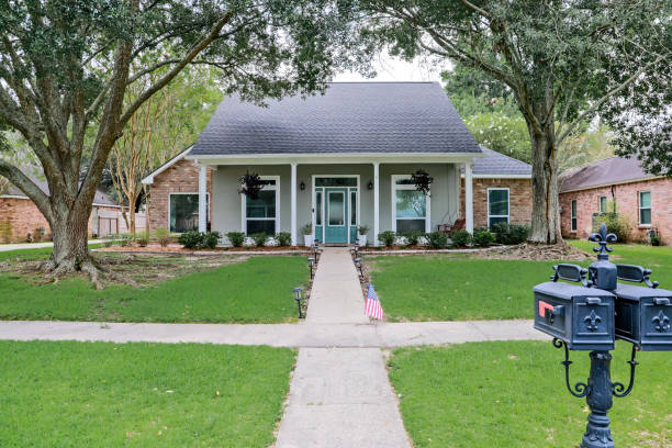 una vista frontal de una casa renovada acadiana con columnas, aceras y una colorida puerta principal recientemente comprada con el cambiante mercado inmobiliario - corto fotografías e imágenes de stock