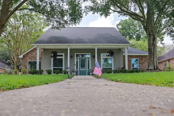 Photo of A front view of an Acadian renovated home with columns, sidewalks and a colorful front door recently purchased with the changing real estate market