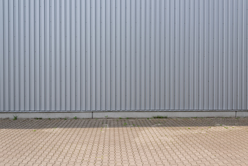 Muro exterior de almacén realizado en chapa de aluminio y carretera asfaltada en zona exterior como imagen de fondo. photo