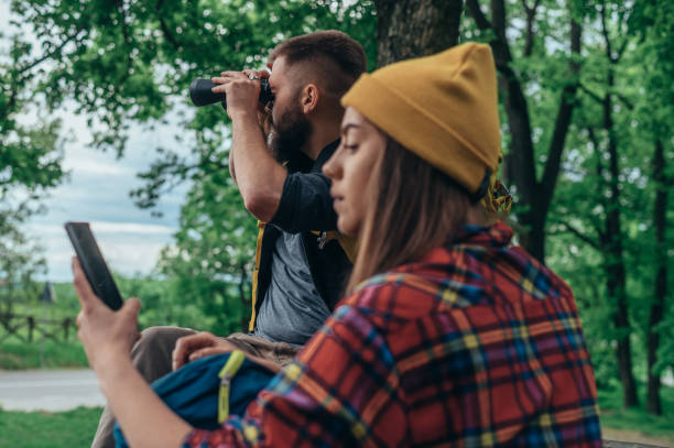 Couple of hikers using binoculars and a smartphone while out in the nature