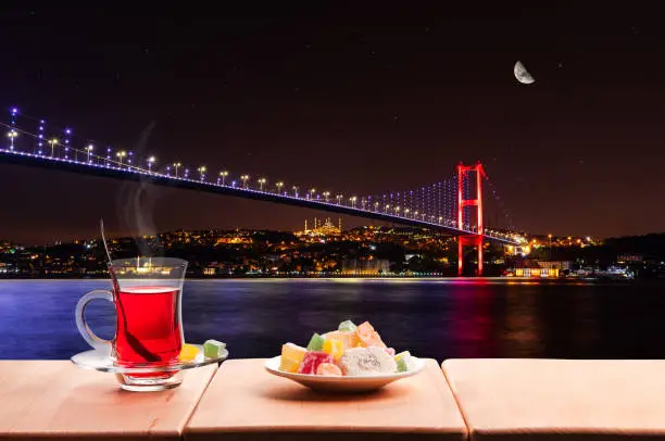 Illuminated Bosphorus bridge at night and traditional turkish tea, Istanbul.