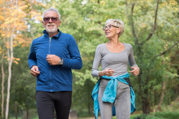 istock Smiling senior couple jogging in the park 1332192550