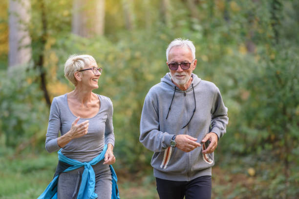 istock Smiling senior couple jogging in the park 1332193408