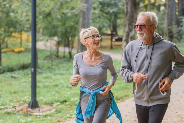 istock Smiling senior couple jogging in the park 1332194289