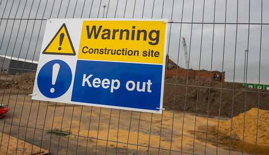 Close up of a Construction site sign on a metal fence