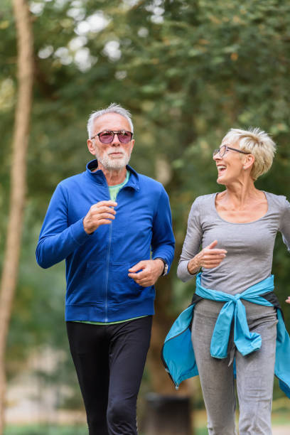 istock Smiling senior couple jogging in the park 1332195072