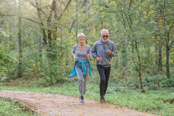 istock Smiling senior couple jogging in the park 1332196792