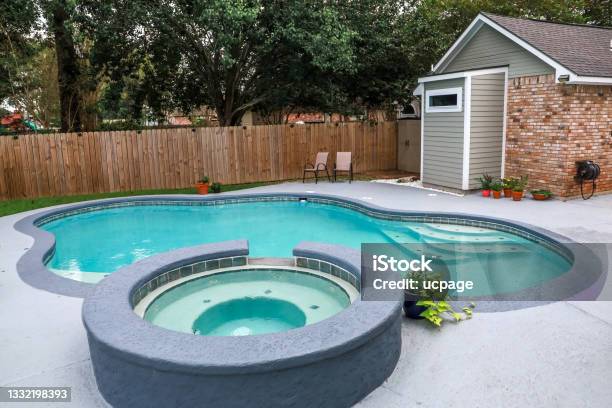 A Large Free Form Gray Grey Accent Swimming Pool With Turquoise Blue Water In A Fenced In Backyard In A Suburb Neighborhood Stock Photo - Download Image Now