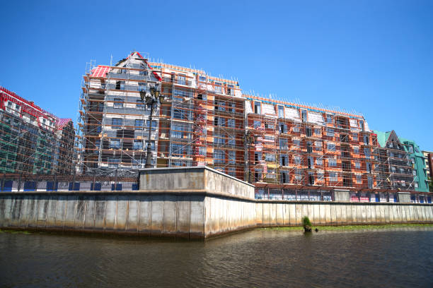 cantiere con impalcature su nuovo edificio sulla riva del fiume, cielo cristallino blu - clear sky residential district house sky foto e immagini stock