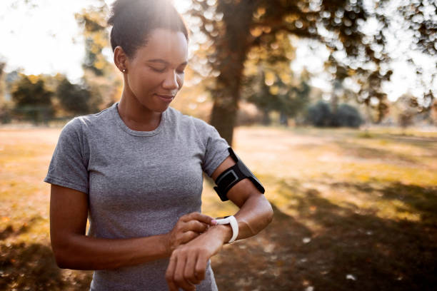 スマートウォッチを見てワークアウトの準備をしているアフリカ系アメリカ人のジョガー - arm band ストックフォトと画像