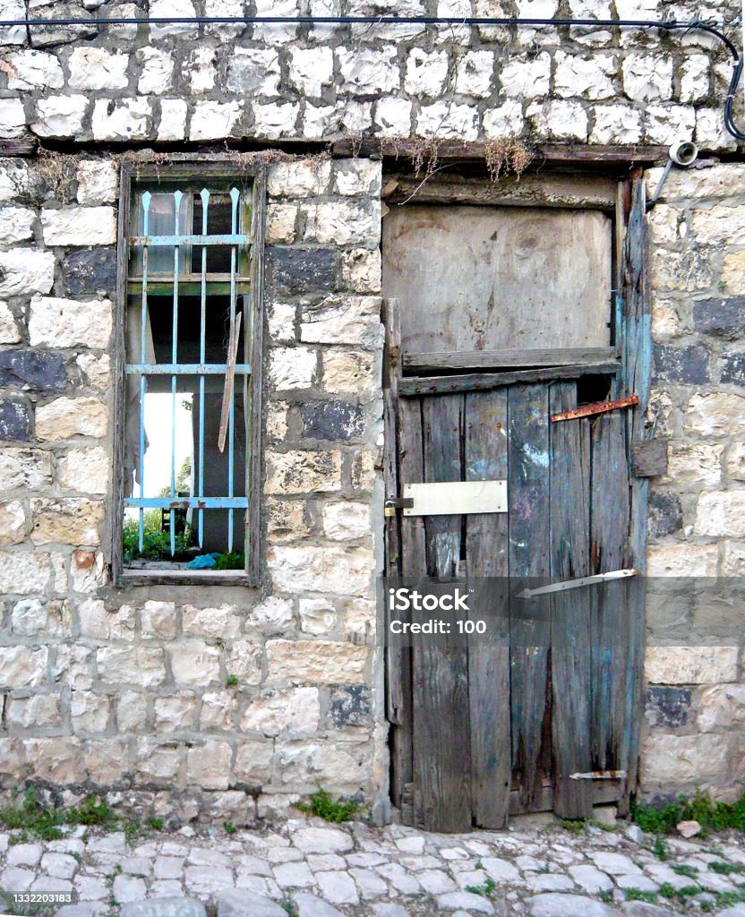 Part of an abandoned house with crumbling walls, broken glass, boarded up dilapidated door and an old pavement Part of an abandoned house with crumbling walls, broken glass, a boarded up dilapidated door and an old pavement Abandoned Stock Photo