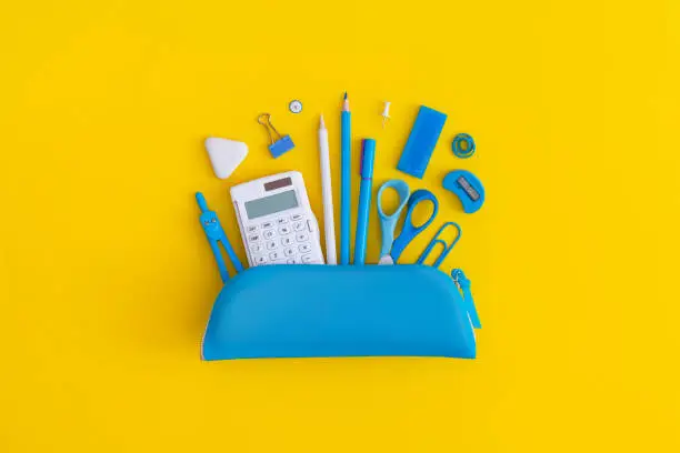 Pencil case with school stationery on a yellow background. Top view. Flat lay. Back to school concept.